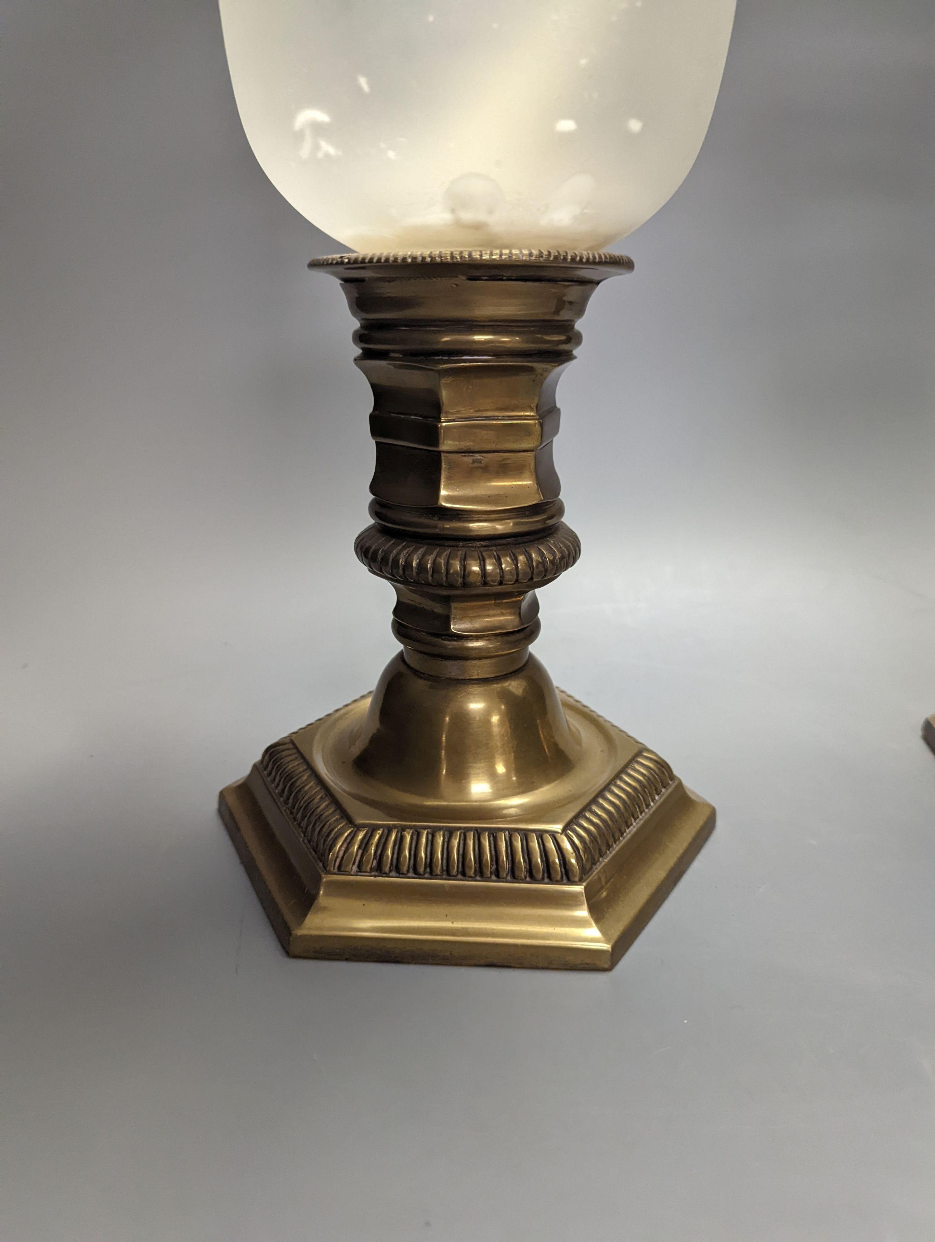 A pair of brass lamps with part frosted glass storm shades, height 45cm